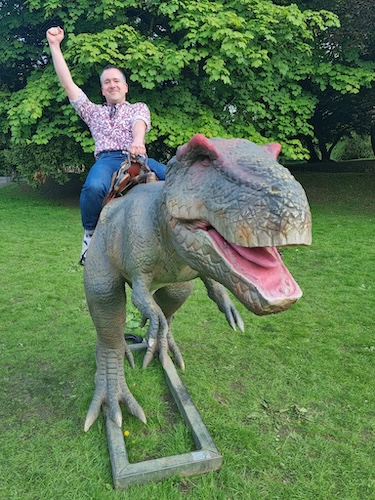 Chris riding on the back of a dinosaur sculpture